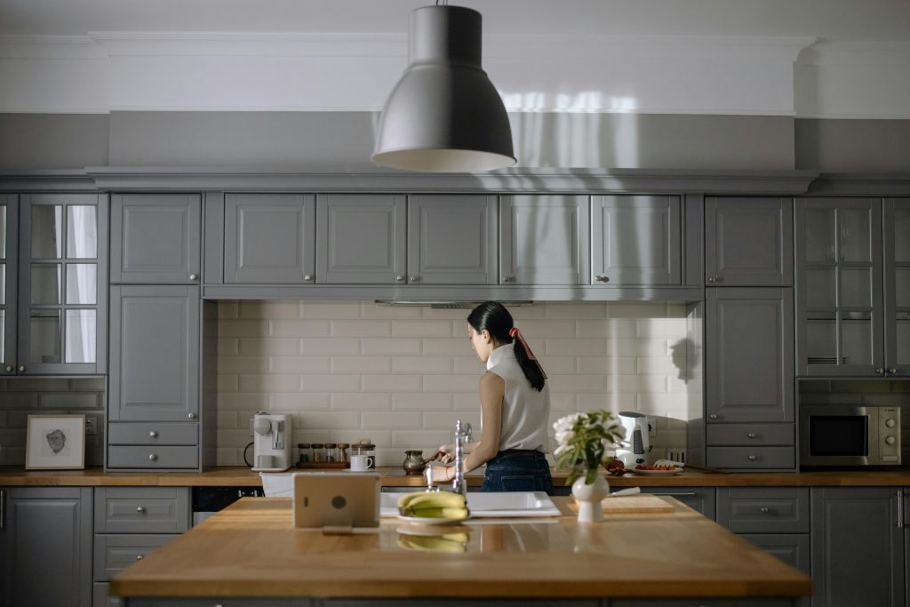 Woman cooking in a contemporary kitchen with gray cabinets and wooden countertops.